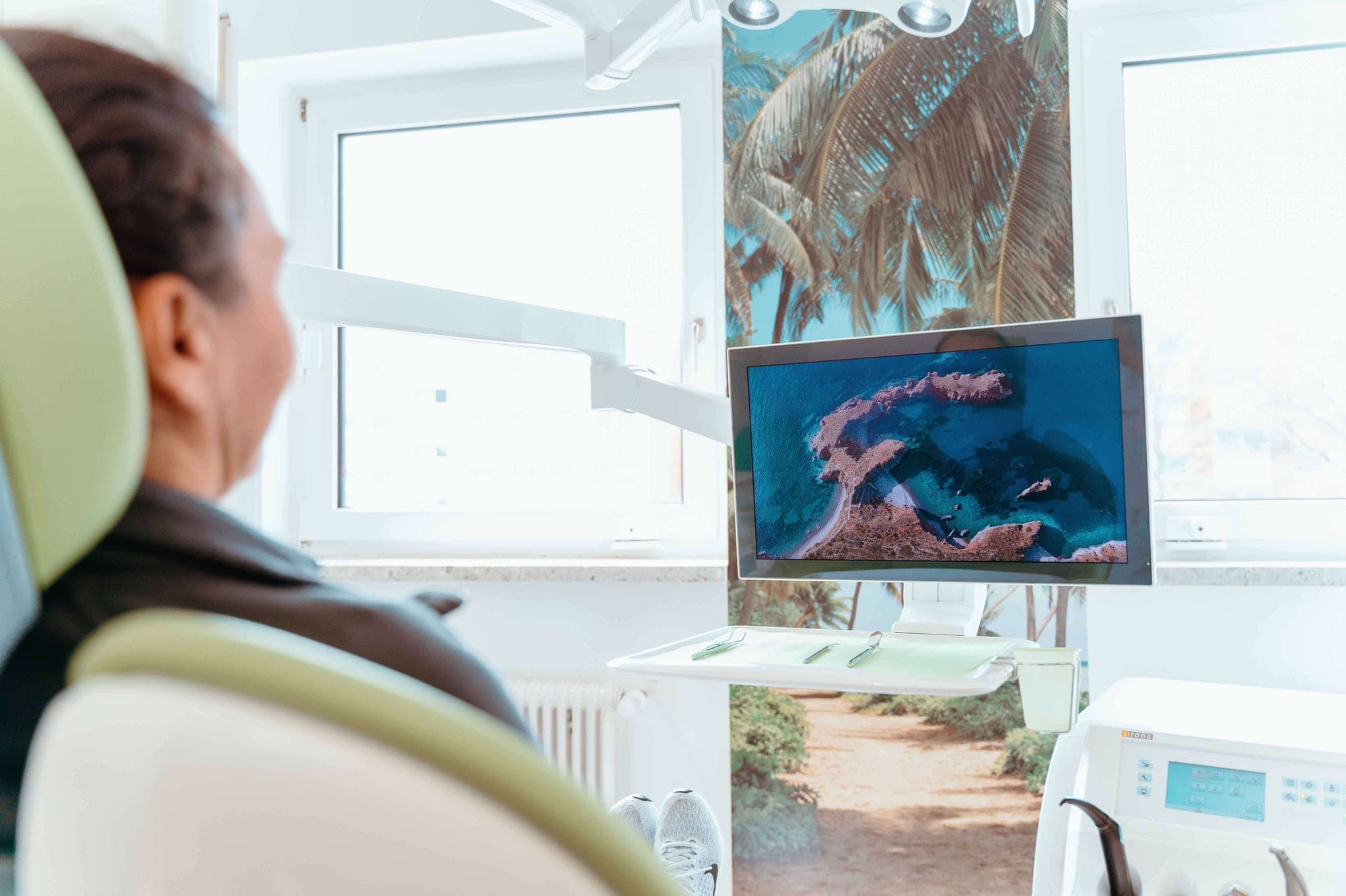 Patient im Behandlungsstuhl mit Blick auf den Bildschirm