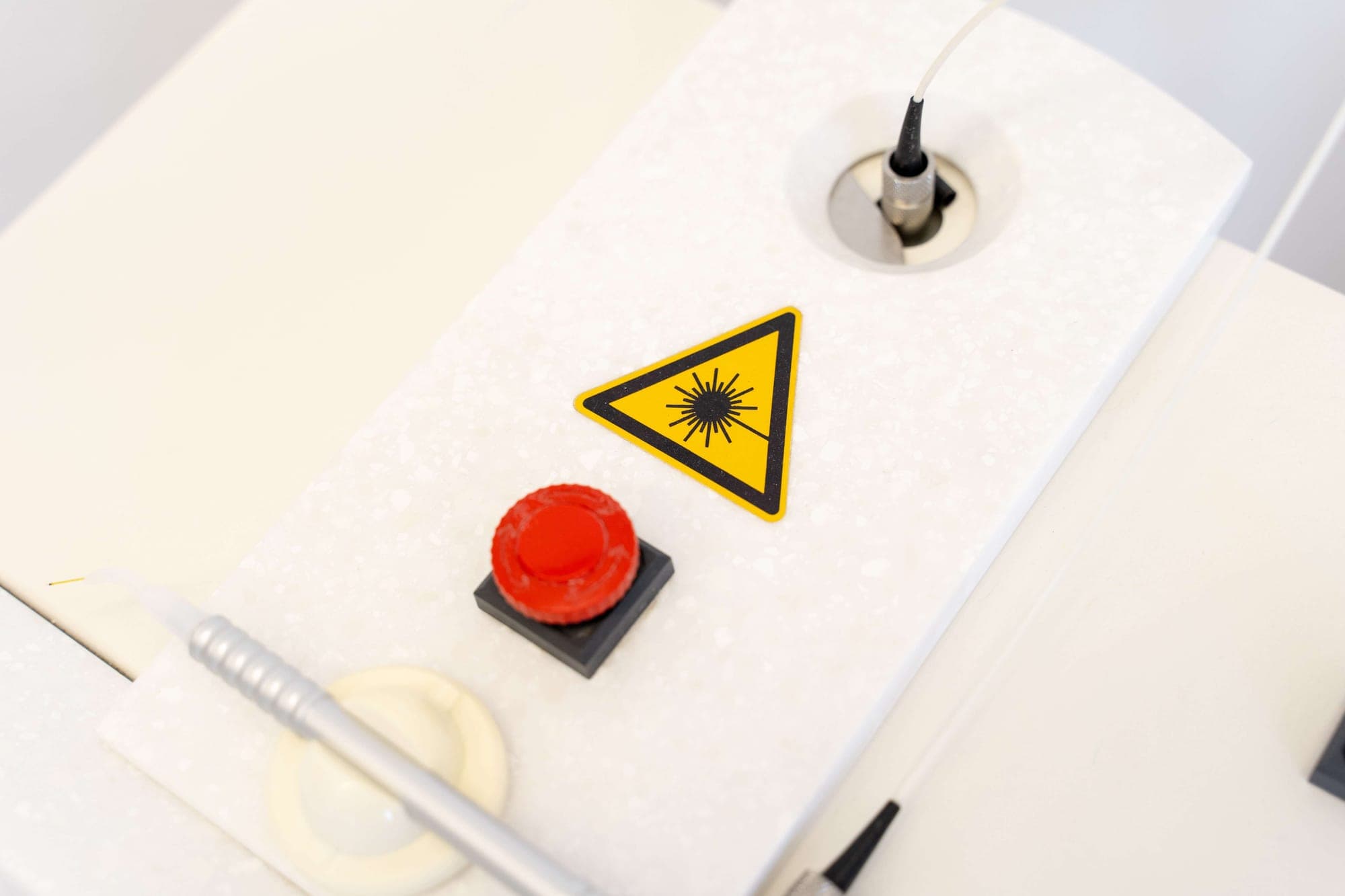 Dentallaser mit Warnsymbol und Handstück für schonende Laserbehandlungen